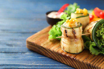 Tasty zucchini rolls with vegetables on wooden board