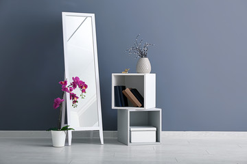 Naklejka premium Big mirror with furniture near color wall in room