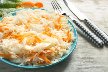 Plate with delicious sauerkraut on light wooden table, closeup