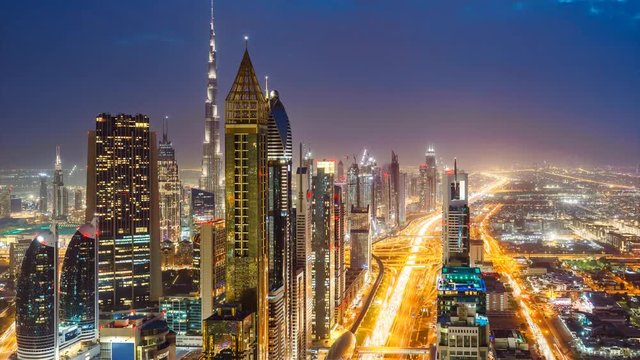 Scenic nighttime skyline of downtown Dubai, United Arab Emirates. Aerial view on highways and skyscrapers in the distance. 4K day-to-night transition timelapse.
