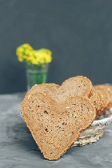 Rye bread in the shape of heart cut into slices on a gray background