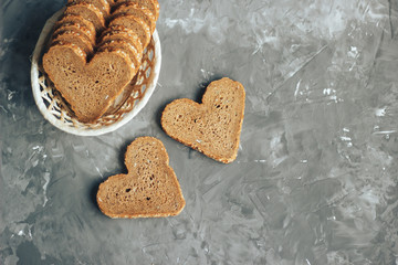 Rye bread in the shape of heart cut into slices on a gray background