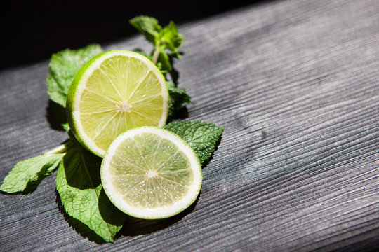 Green lime with slice and mint on black background with copy space