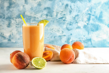 Glass with fresh peach smoothie on light table