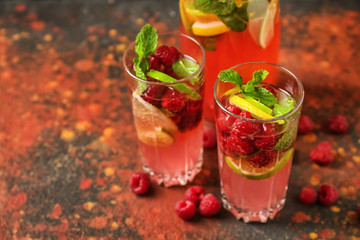 Glasses of fresh raspberry mojito on color table