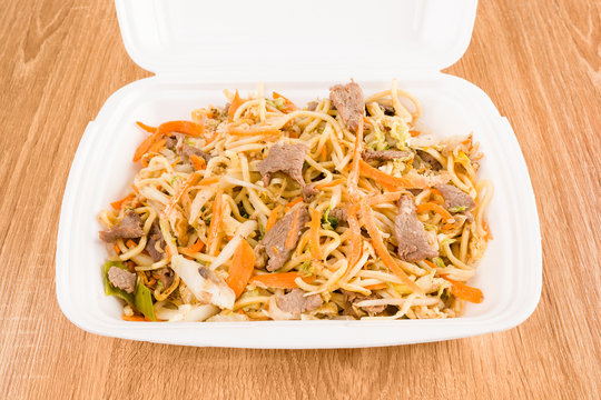 Asian noodles with pork in take away box.
