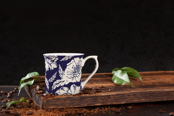 Cup of coffee with leaves and roasted beans.