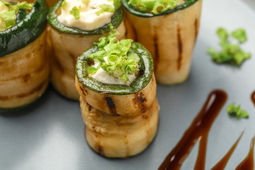 Tasty zucchini rolls with cheese on plate, closeup
