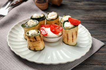 Tasty zucchini rolls with cheese and sauce on plate
