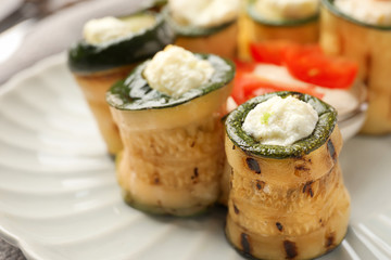 Tasty zucchini rolls with cheese on plate, closeup
