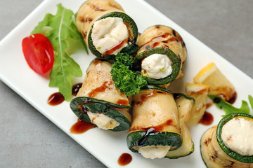 Tasty zucchini rolls with cheese and sauce on plate