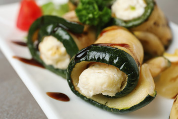 Tasty zucchini rolls with cheese on plate, closeup