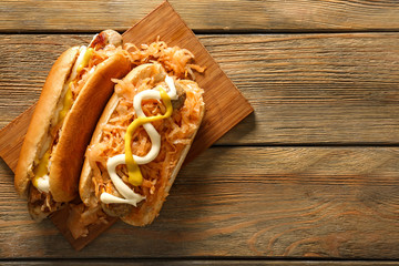 Tasty hot dogs with stewed cabbage on wooden board