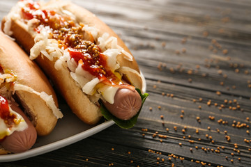 Tasty hot dogs with sauerkraut and sauce on wooden table