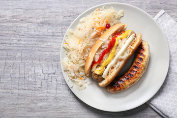 Plate with tasty hot dog and sauerkraut on grey table