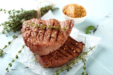 Delicious grilled steaks with thyme on light table