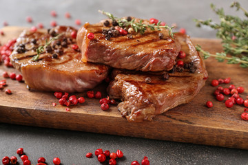 Delicious grilled steaks with spices on wooden board