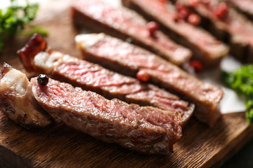 Cut grilled steak on wooden board, closeup