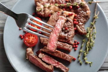 Fork with piece of tasty grilled steak, closeup