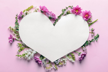 Heart shaped sheet of paper with beautiful flowers on color background