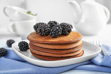Tasty chocolate pancakes with blackberries on plate