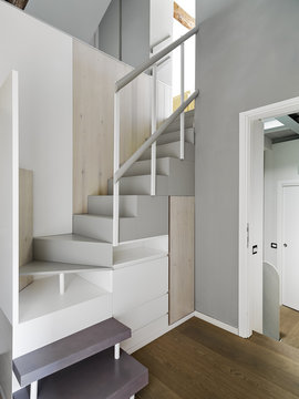 in the foreground the modern wooden staircase with drawers and hidden wardrobes.overlooking the landing