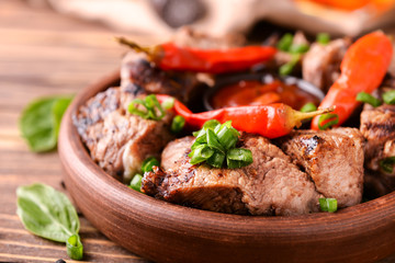 Bowl with delicious shish kebab on wooden table, closeup