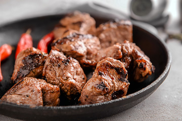 Frying pan with delicious shish kebab on table, closeup