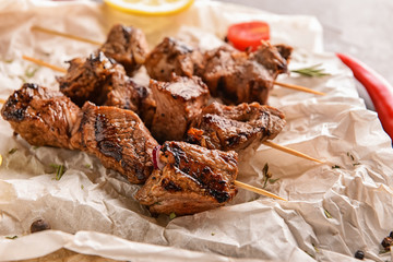 Skewers with delicious shish kebab on parchment paper, closeup
