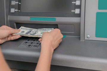 Woman picking up the money from a cash machine, closeup
