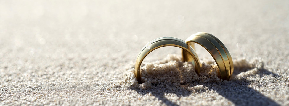 Gold wedding rings at the beach Banner design with copy space. Summer wedding background.