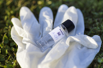 Illustration with mock up of Novichok agent (A-234) bottle and white rubber gloves on grass. Fictitious title on bottle in Russian: Novichok