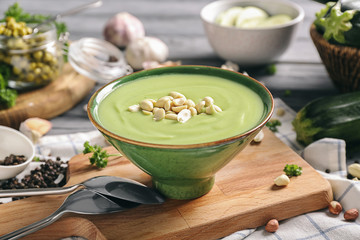 Bowl with tasty zucchini soup on wooden board