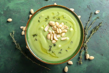 Bowl with tasty zucchini soup and peanuts on color table