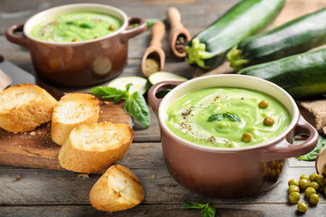 Tasty zucchini soup in saucepan on wooden table