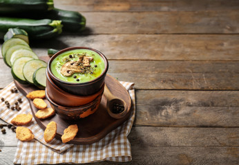 Bowls with tasty zucchini soup and mushrooms on wooden table