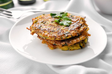 Plate with zucchini pancakes on table