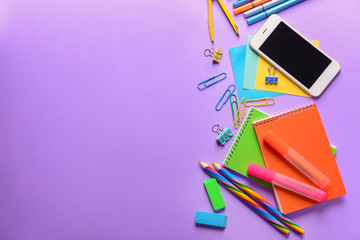 Set of school stationery with mobile phone on color background