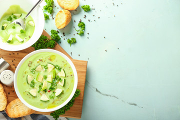Bowls with delicious zucchini soup on light table