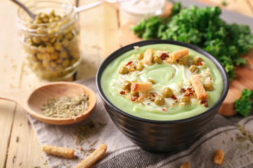 Bowl with delicious zucchini soup on table