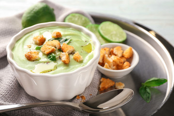 Bowl with delicious zucchini soup and croutons on plate