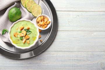 Composition with delicious zucchini soup on light wooden table