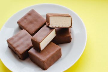 Chocolate sweets with white souffle on a plate on a yellow background.