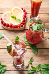 Jug and glass of fresh raspberry lemonade on wooden table