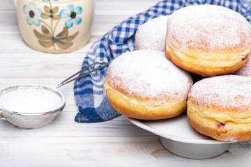Traditional Polish donuts with powdered sugar on wooden background. Tasty doughnuts with jam.
