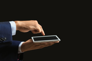 Businessman with tablet PC on dark background