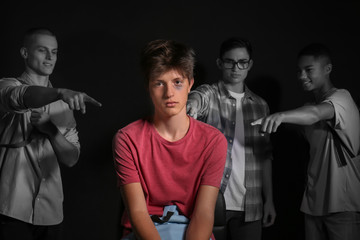Teenagers bullying boy on dark background