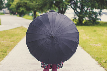 black classic umbrella cycle shape in human hand on unfocused bokeh natural park environment