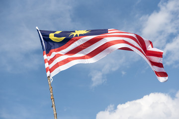 Malaysia flag also known as Jalur Gemilang wave with the blue sky. People fly the flag in conjunction with the Independence Day celebration or Merdeka Day.