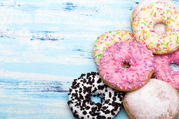 Traditional donuts on white wooden background.  Tasty doughnuts with icing and powdered sugar, copy space